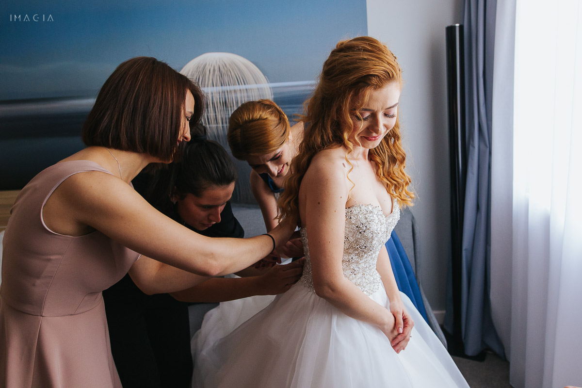 Mireasă îmbrăcând rochia de mireasă, împreună cu domnișoarele de onoare la o nuntă în București, la Hotel Novotel